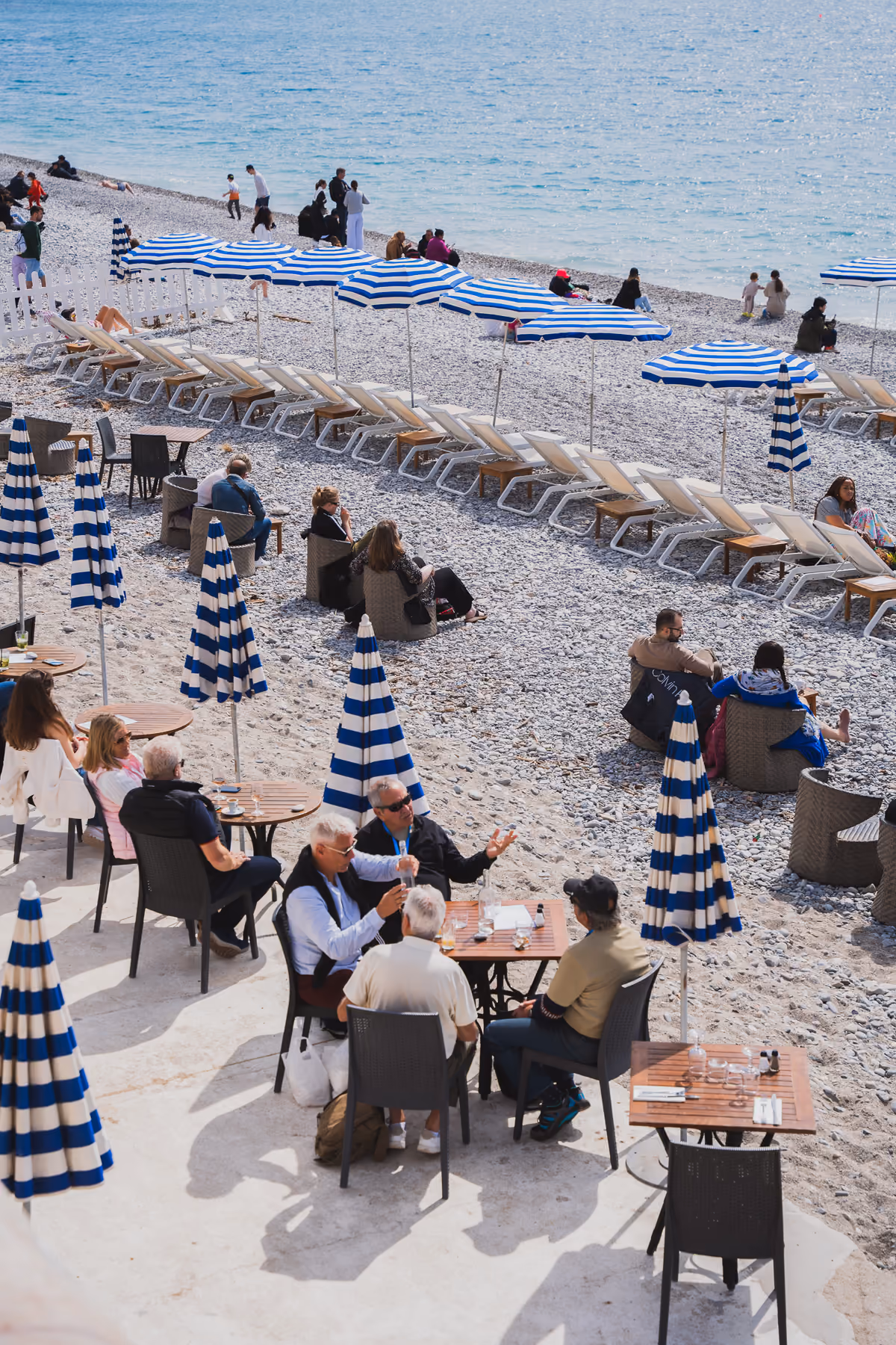 Striped umbrellas and cafe tables on a pebble beach