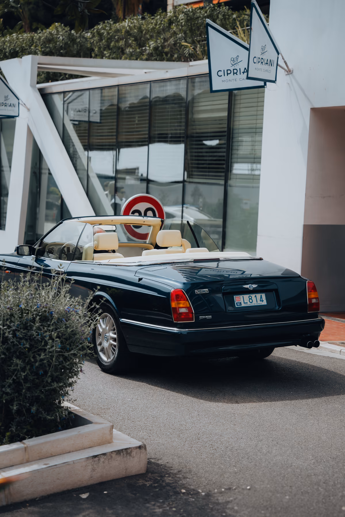 Dark Bentley convertible passing a Cipriani sign